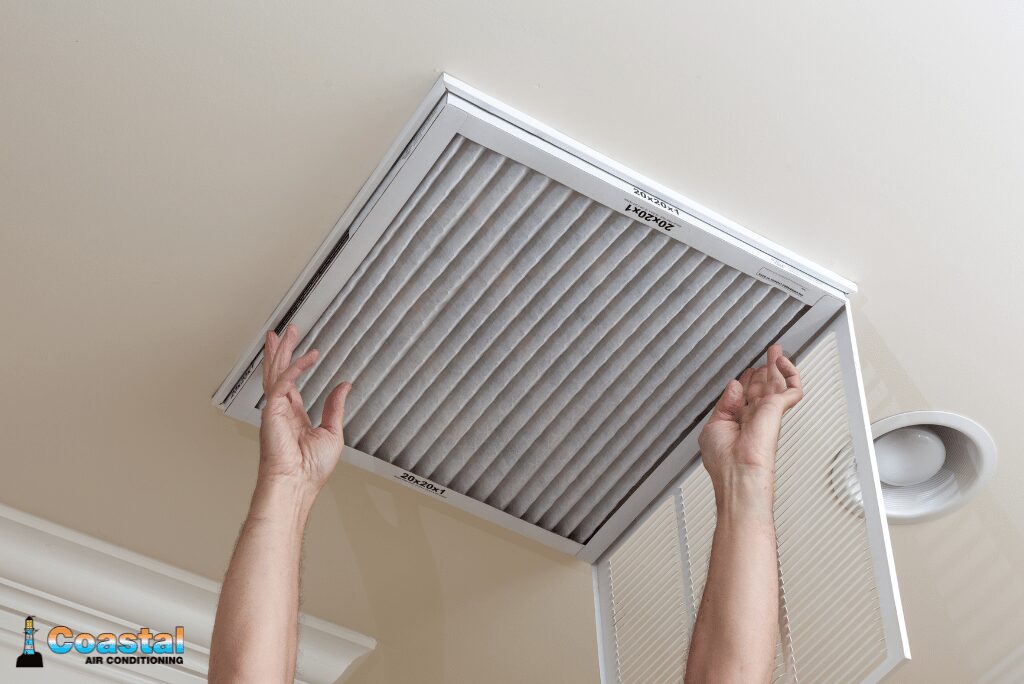 Hands replacing ceiling HVAC air filter